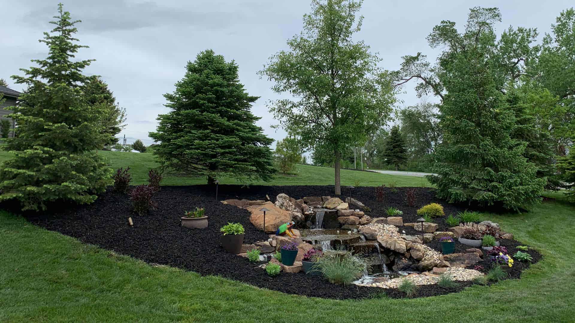 Outdoor Multi Level Water Feature Surrounded By Rocks Mulch Trees